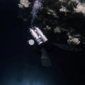 Deep technical diver descending into darkness, highlighting the risks of deep air narcosis.