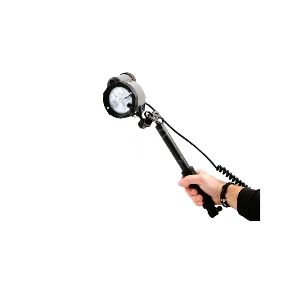 Black handheld spotlight with circular head and coiled cable attached to quick release carbon arm with grip