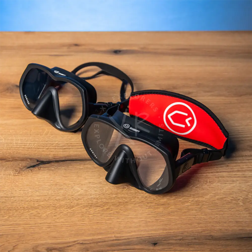 Divesoft sentry frameless diving mask in black with a red neoprene strap and white circular logo