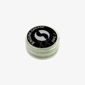 A small clear plastic container with a black lid labeled engine grease for drive system grease 5 ml