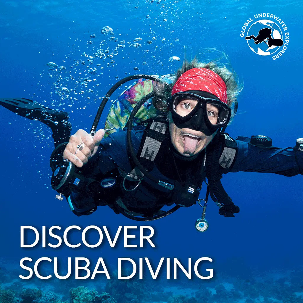 A scuba diver in black gear with a red bandana and clear goggles holding up their hand underwater for gue discover diving