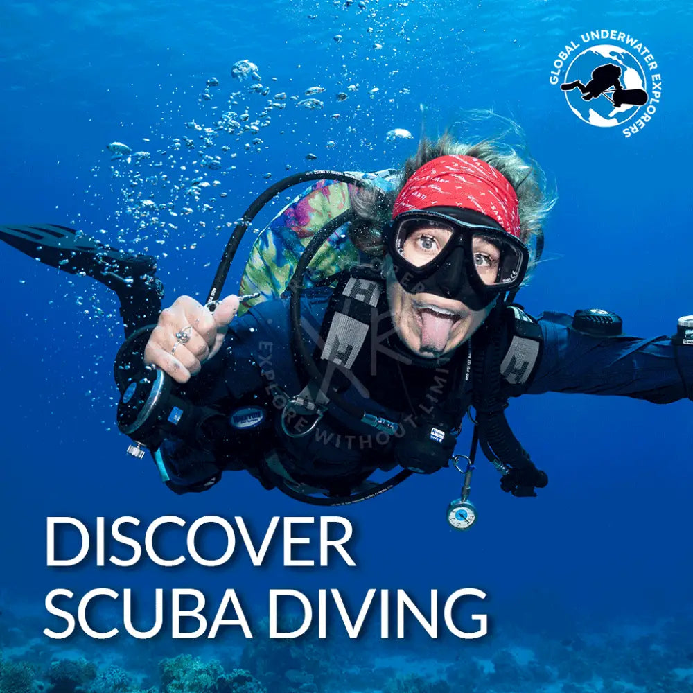 A scuba diver in black gear with a red bandana and clear goggles holding up their hand underwater for gue discover diving