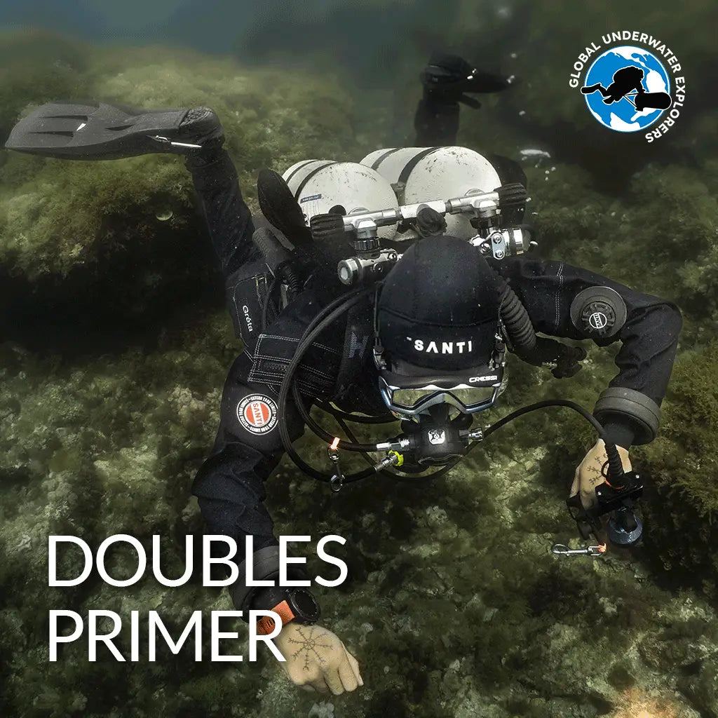 Black wetsuit with santi branding and circular logo on the arm paired with silver scuba gear with dual tanks for gue doubles primer