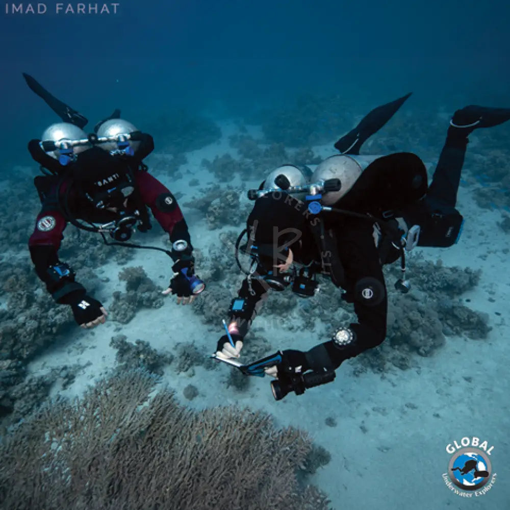 Black wetsuit with santi branding and circular logo on the arm paired with silver scuba gear with dual tanks for gue doubles primer