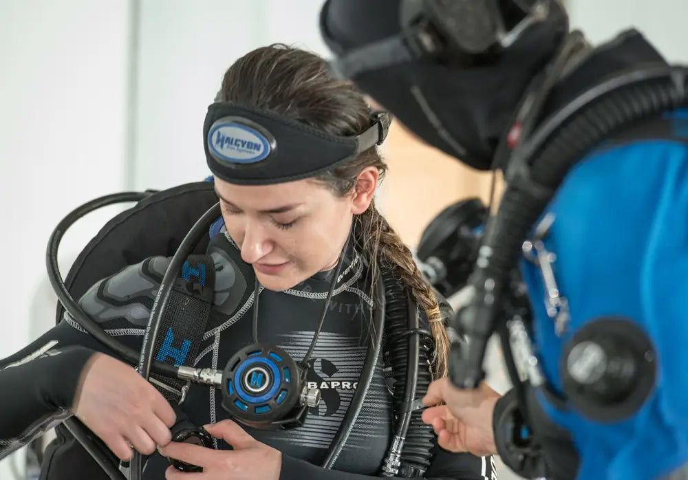 Diver performing a long hose gas drill equipment check before jumping into water with instructor