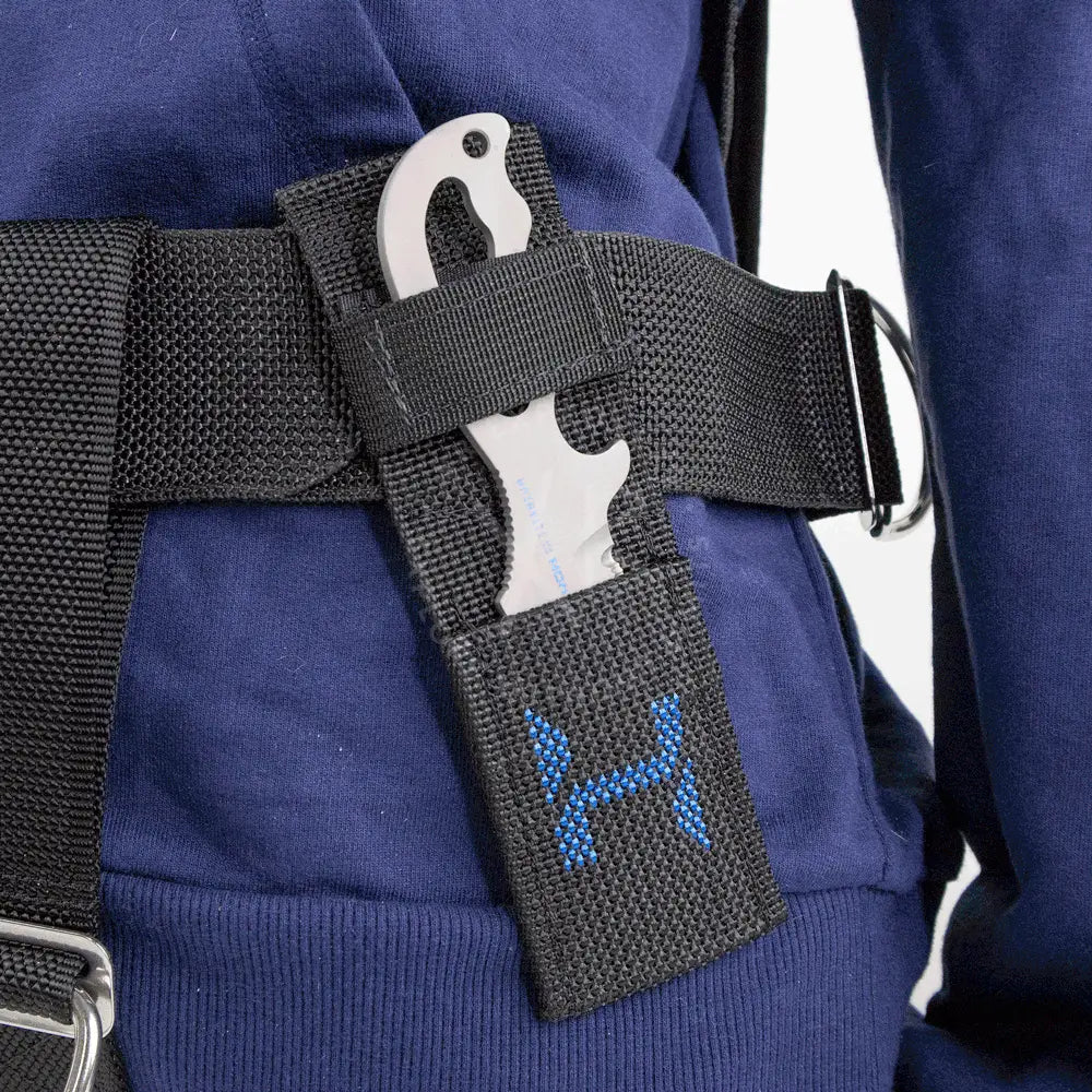 Black mesh harness sheath with blue embroidered logo holding a silver halcyon explorer knife with titanium blade