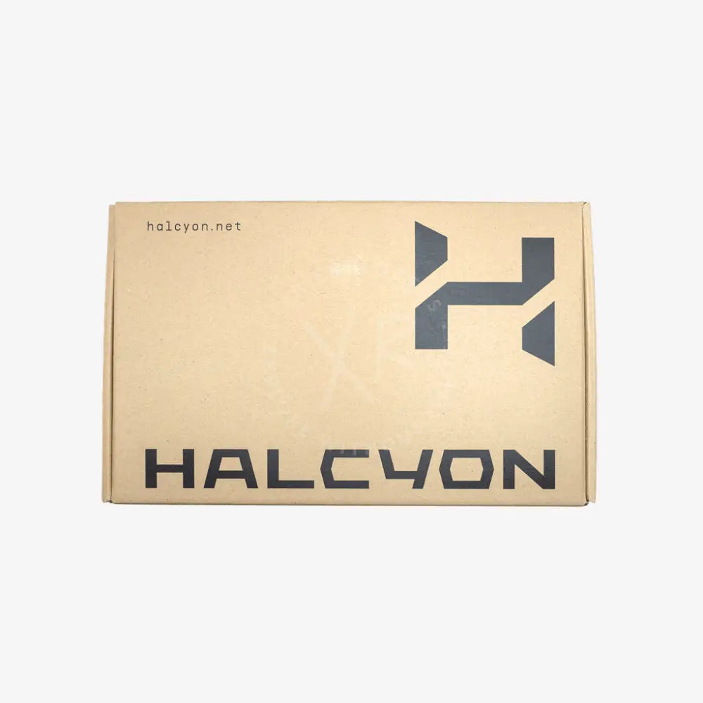 A square cardboard box with a kraft beige background, featuring a dark gray stylized 'H' logo and the word 'HALCYON' printed prominently on the front, with 'halcyon.net' in smaller text at the upper left.
