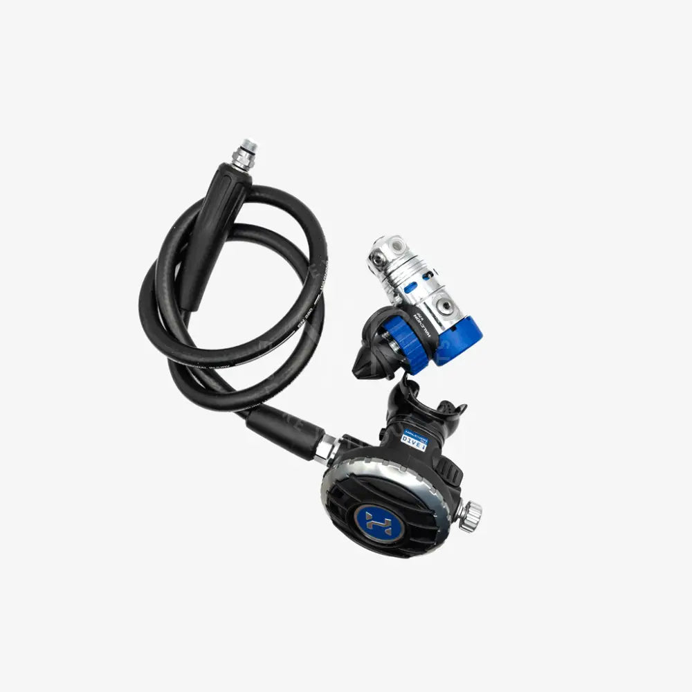 A black scuba diving regulator with a coiled black hose and a silver and blue TCS regulator connector, shown on a light gray background.
