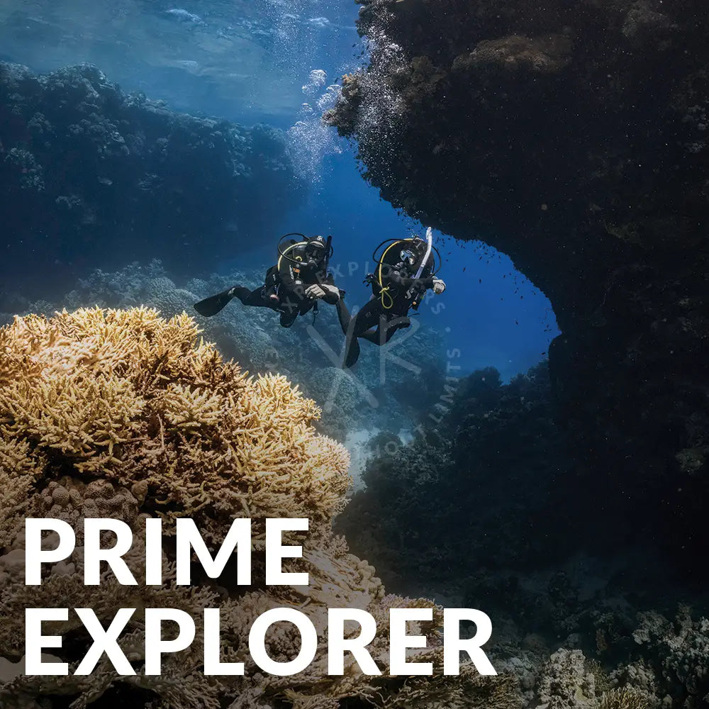Two scuba divers in black wetsuits explore a vibrant coral reef in the prime explorer bundle set