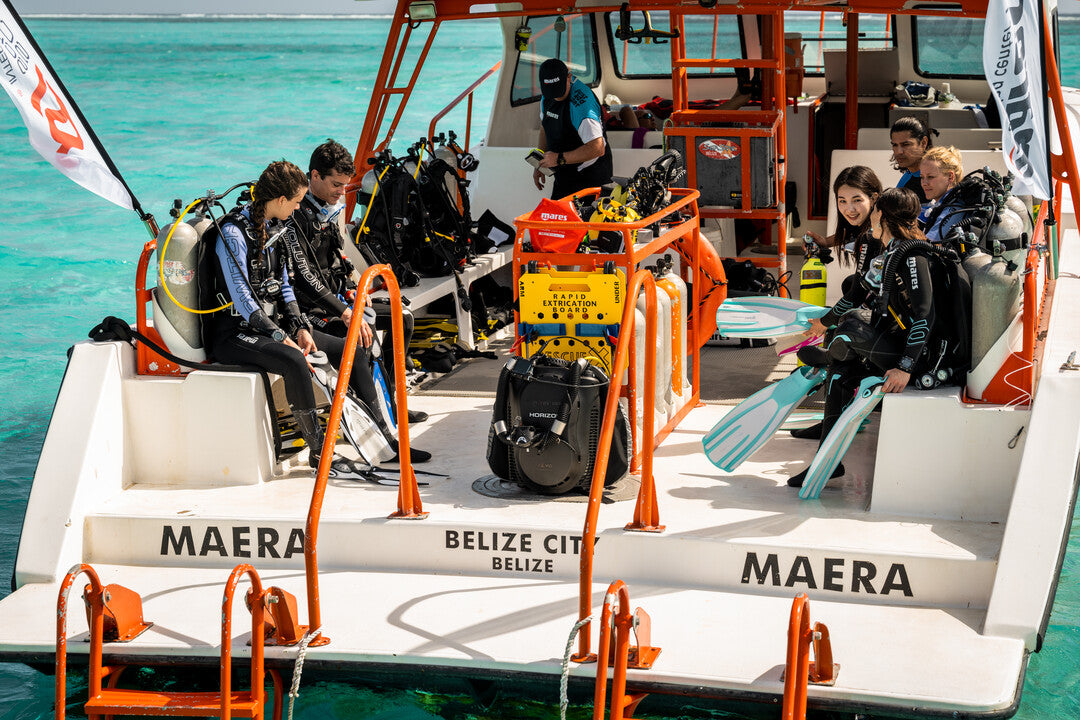 A group of divers on a boat with diving equipment, preparing for a dive trip.