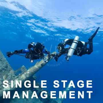 Two scuba divers in blue and black suits explore an underwater wreck using single stage mastery oxygen tanks