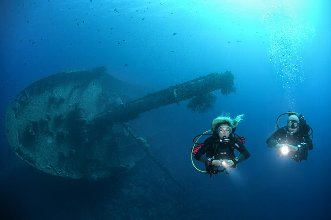 Dive guide leading a group underwater while maintaining team contact in Qatar